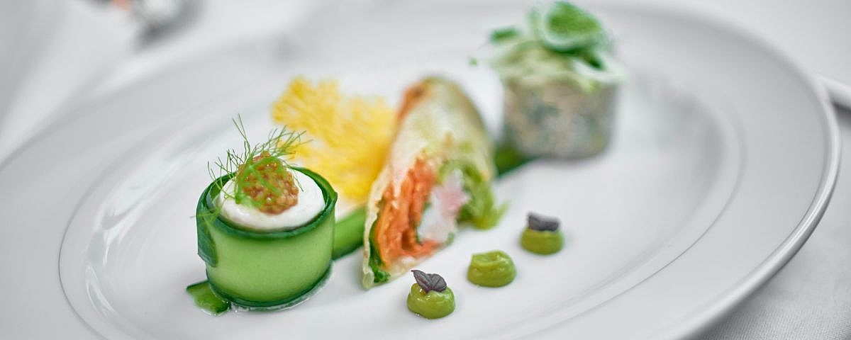 Schloss Wackerbarth The artfully presented dish combines fresh ingredients such as cucumber, fish, foam, fine creams and vegetable garnish in a harmonious colour composition on a white plate.