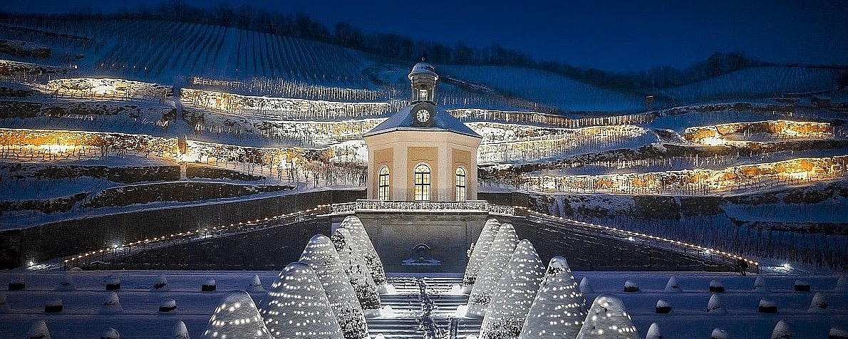 Wackerbarth Castle at night in the snow-covered vineyard, festively illuminated with fairy lights up to the Belvedere.